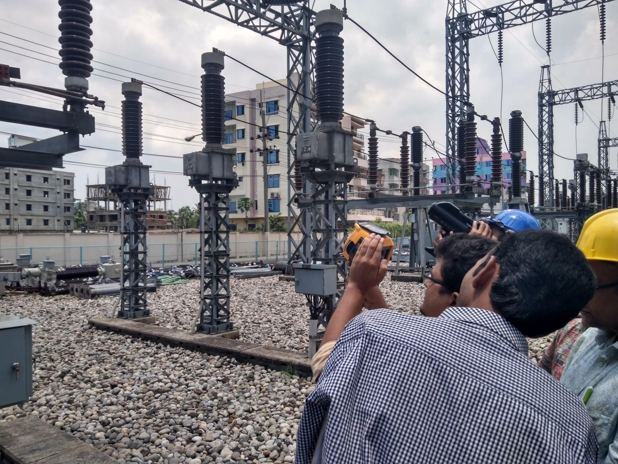 Engineers demonstrating thermal imaging with Fluke camera at PGCB substation in Bangladesh